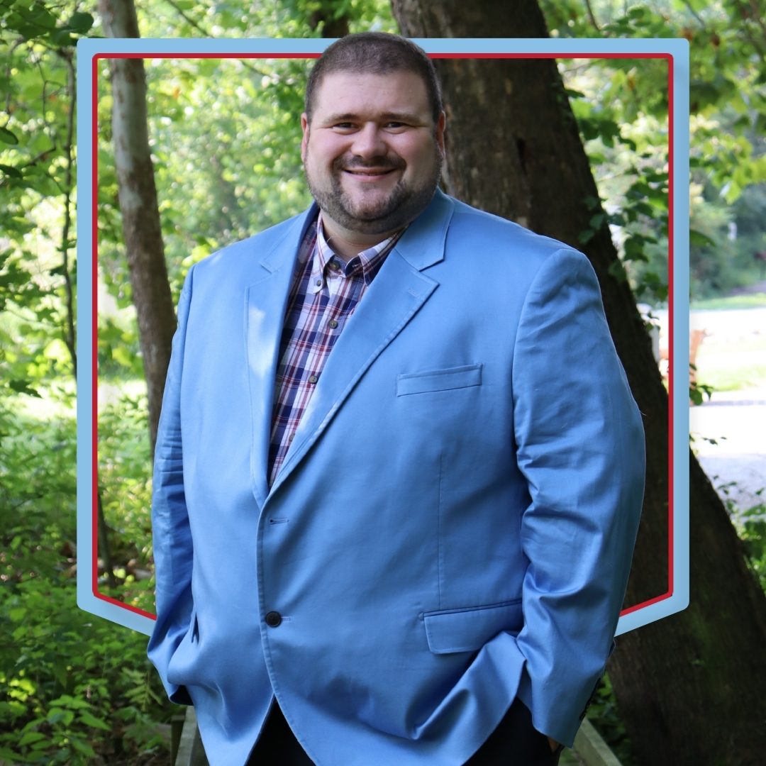 Sam Lovelace poses in front of a wooded background.